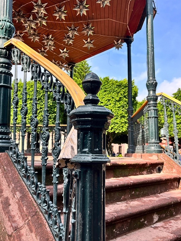 Side view of El Jardín Kiosk in San Miguel de Allende, highlighting a close-up of its worn-out terracotta stairs with intricate details and textures.