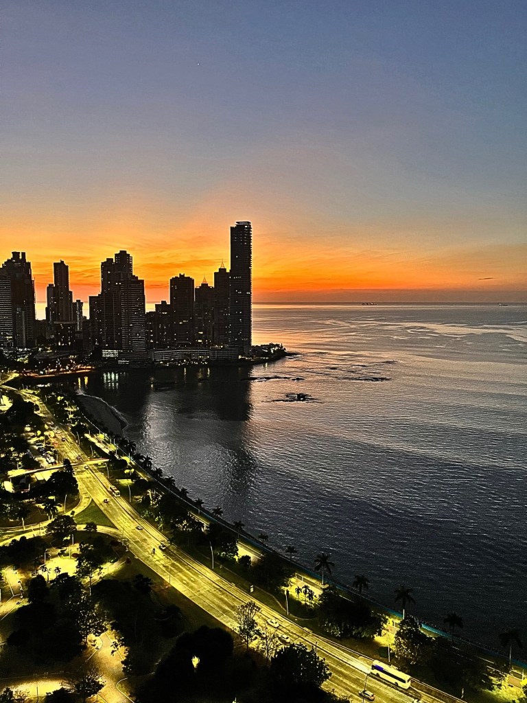 Crimson sunset behind Panama City’s skyline, with high-rise buildings in silhouette along the Cinta Costera and a glowing sky fading into night.
