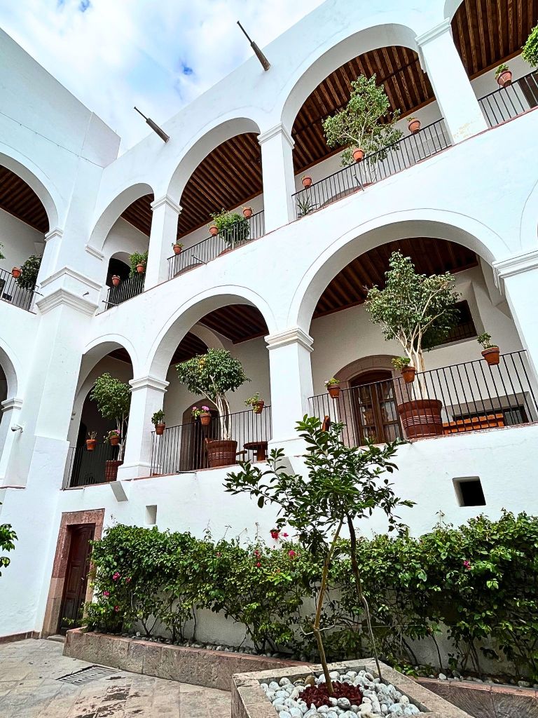 Interior courtyard of Casa de Mayorazgo de la Canal showing two upper levels and nine stone arches, with soft shadows and white walls evoking a sense of timeless elegance.