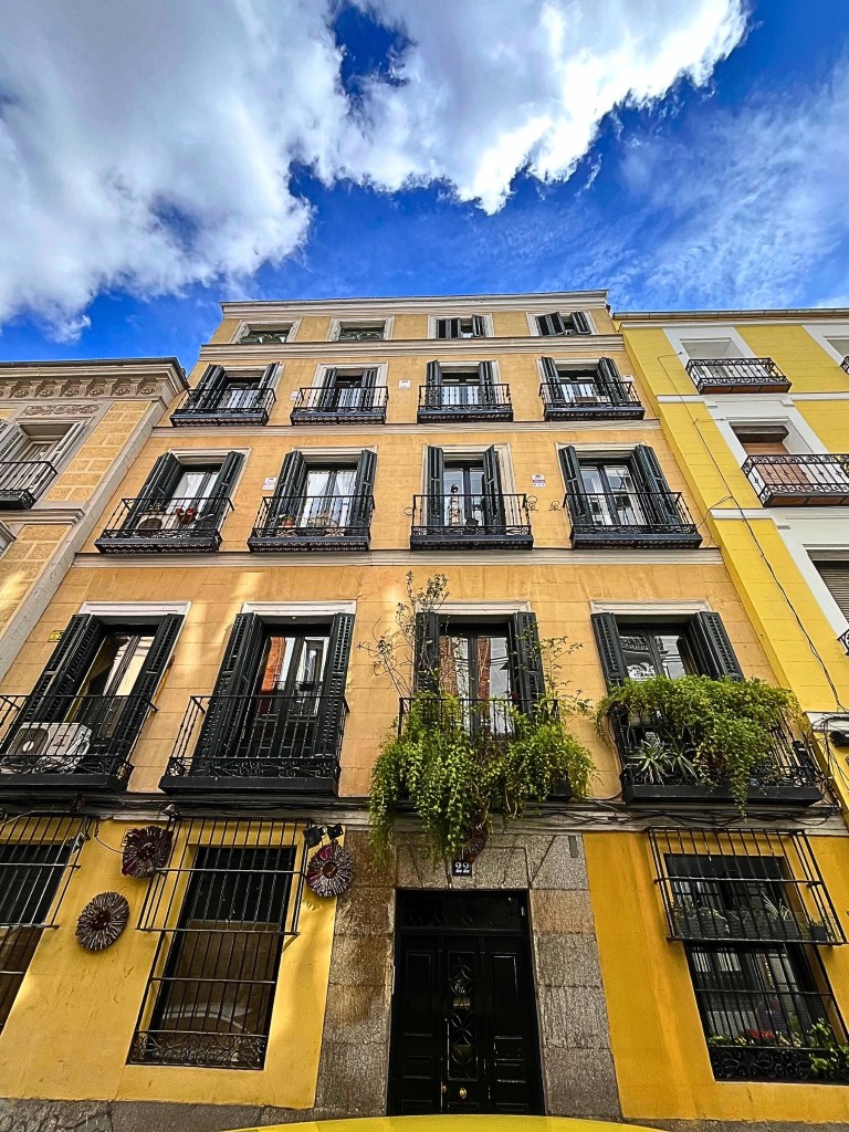 A historic building in Madrid's Embajadores neighborhood with ornate balconies and a warm-colored façade.​