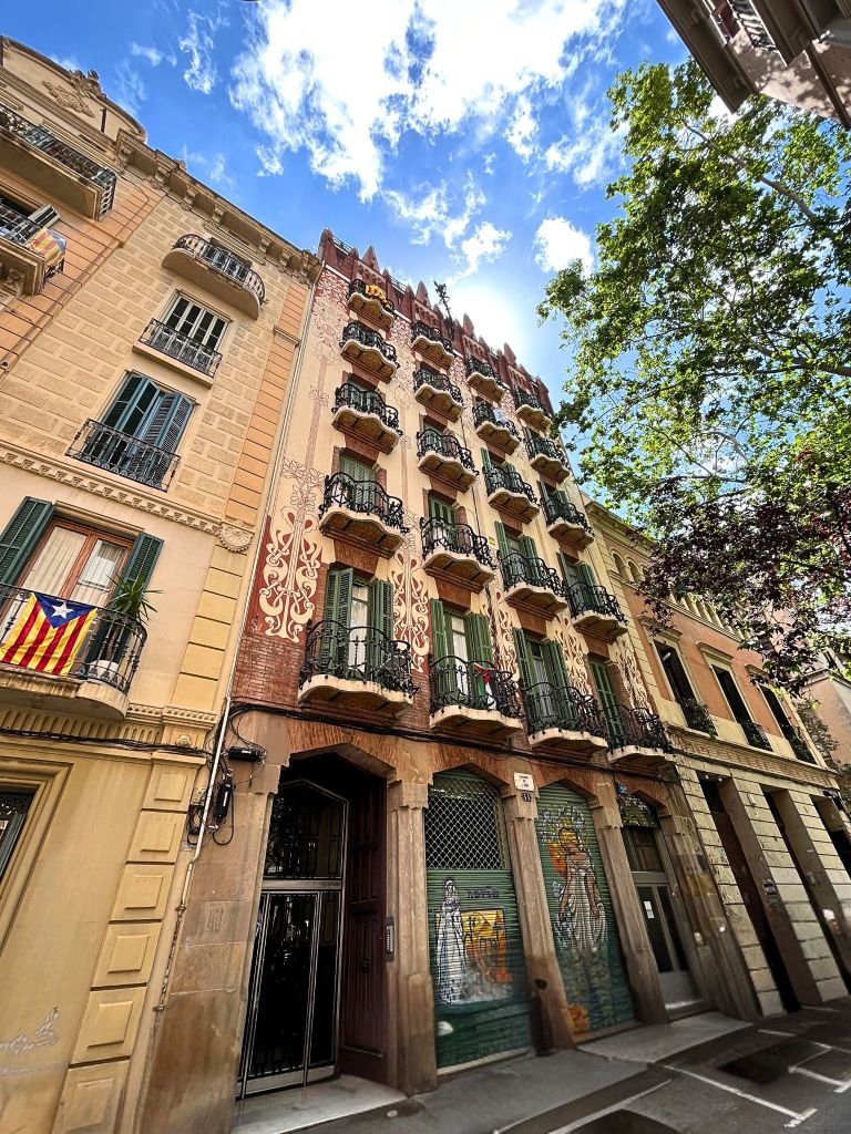 Casa Rubinat seen from below in a dramatic vertical angle, showing its modernist design reaching toward the sky in Gràcia, Barcelona.