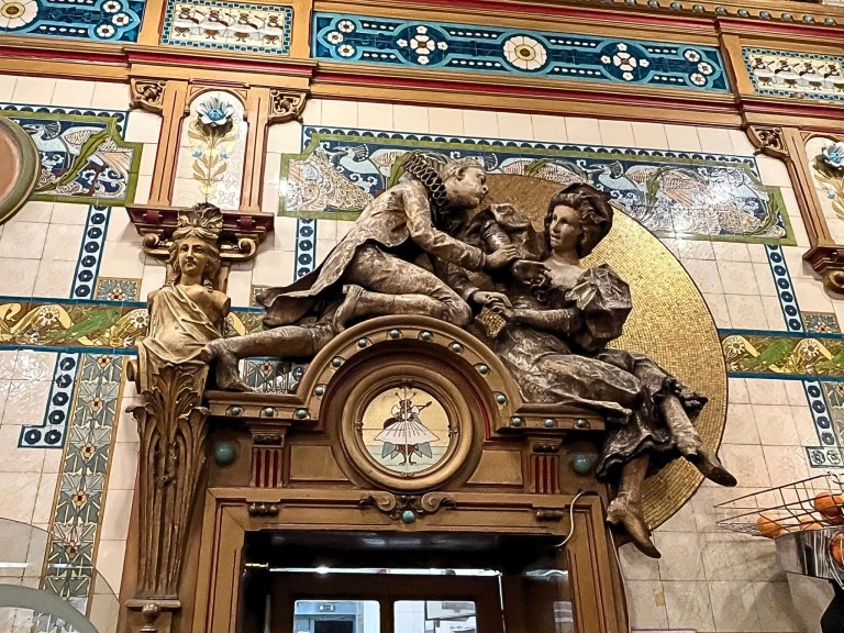 Detailed ceramic panels featuring whimsical characters and natural motifs, a hallmark of La Cigale’s interior style.