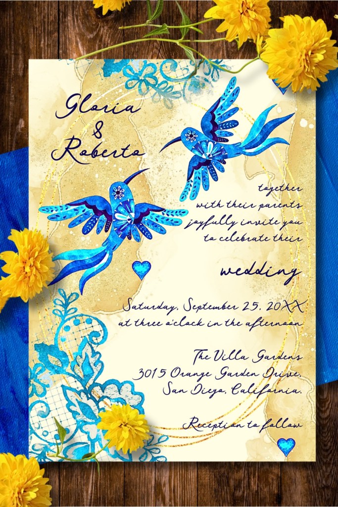 Close-up of luxury blue hummingbird Baroque wedding invitation featuring watercolor birds, cobalt hearts, and golden lace flourishes — Mexican-inspired artistic stationery.