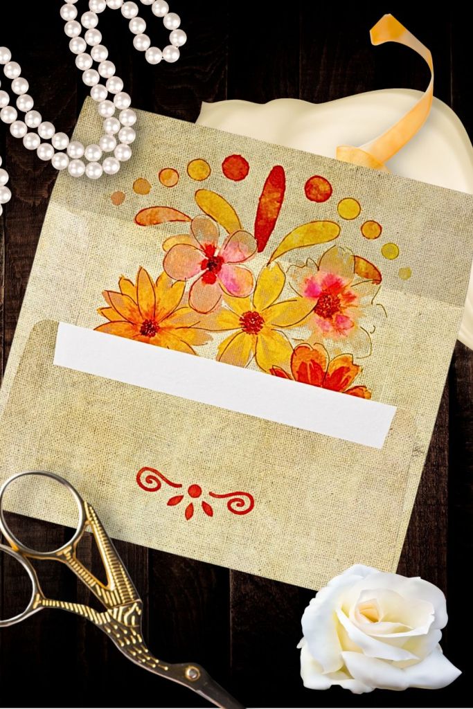 Rustic linen wedding envelope with Sacred Heart floral design in warm gold, coral, and marigold hues, accented with pearls, vintage scissors, and a white rose — part of the Sacred Heart Baroque Vintage Wedding Suite.