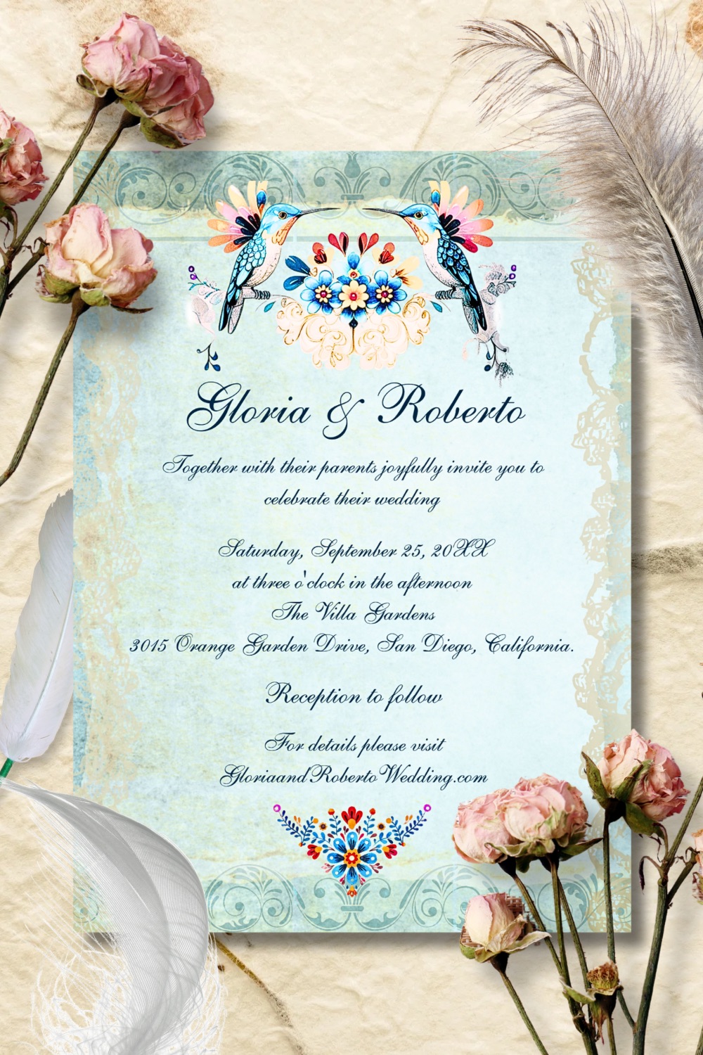 Elegant vintage-style wedding invitation featuring two folk-art hummingbirds and floral motifs on a soft sky-blue lace background — refined and romantic design.