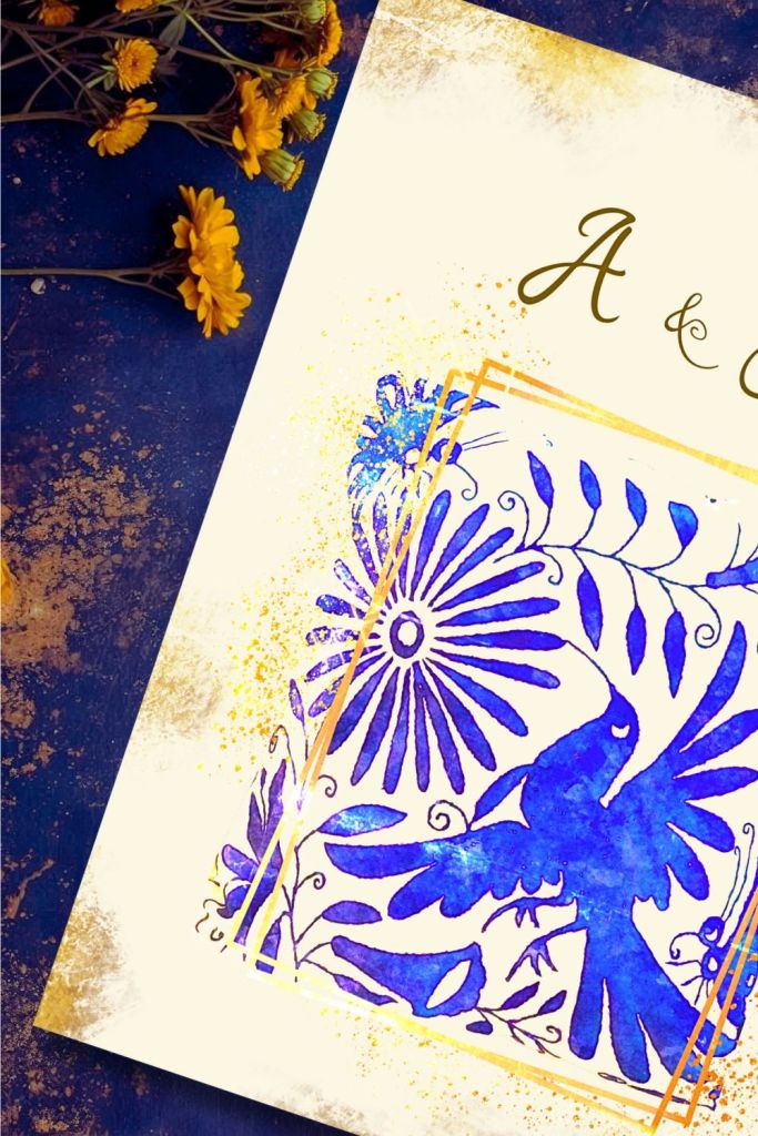 Blue and gold Talavera bird wedding invitation detail with floral folk art motif and gold frame accents on a textured indigo surface